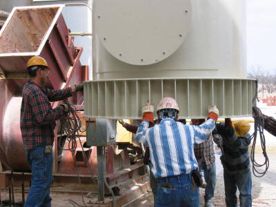 Lowering an exhaust stack base section onto its anchor bolts.